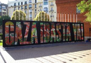 Mural colaborativo facilitado polo colectivo Boa Mistura para a lectura do manifesto na Casa Árabe de Madrid. Sobre un fondo negro, como un caollage de moitas cores e deseños, pódese ler "Gaza basta ya"